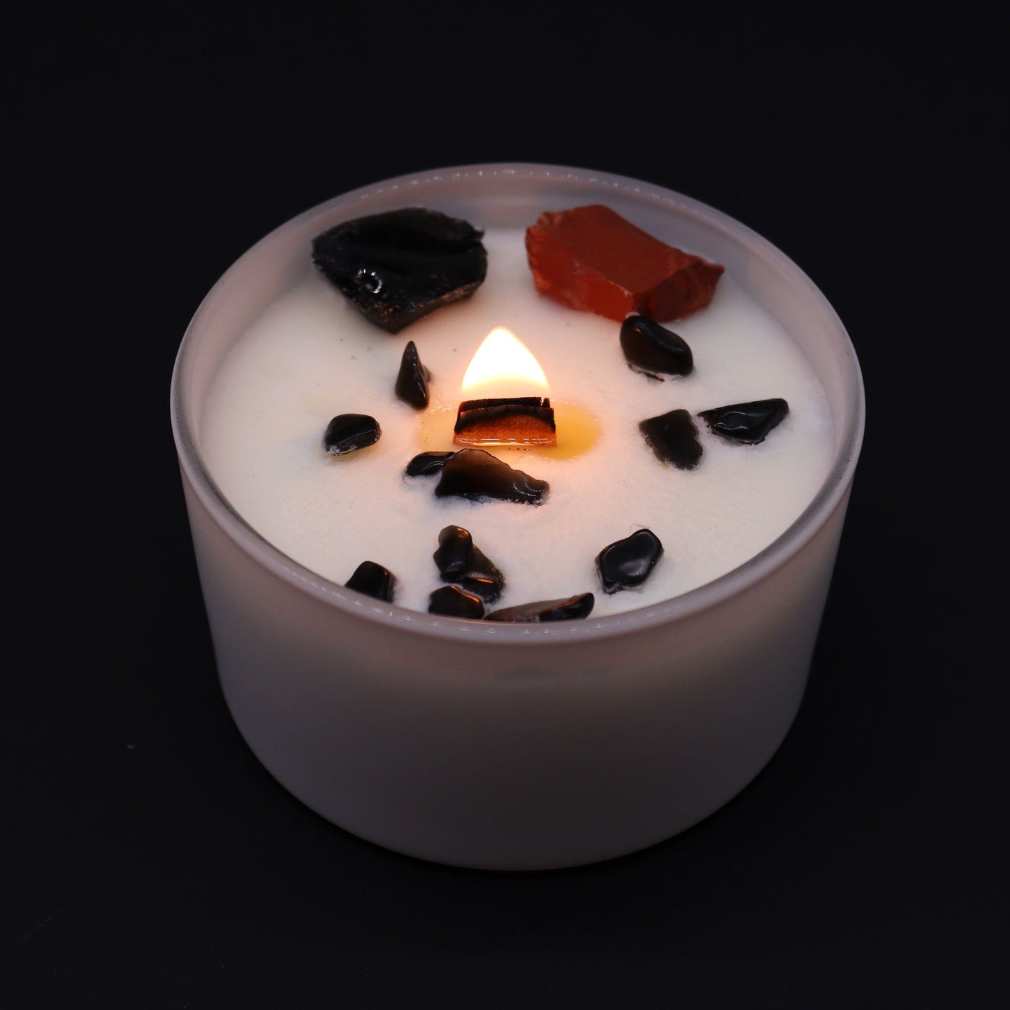 Candle with decorative stones on a black background